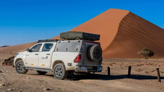 Samochód Toyota Hilux przed wydmą w Soussuvlei w Namibii