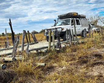 Safari self-drive w Botswanie – samochód terenowy 4x4 z namiotem dachowym pokonuje drewniany most w Rezerwacie Moremi.