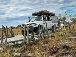 Safari self-drive w Botswanie – samochód terenowy 4x4 z namiotem dachowym pokonuje drewniany most w Rezerwacie Moremi.