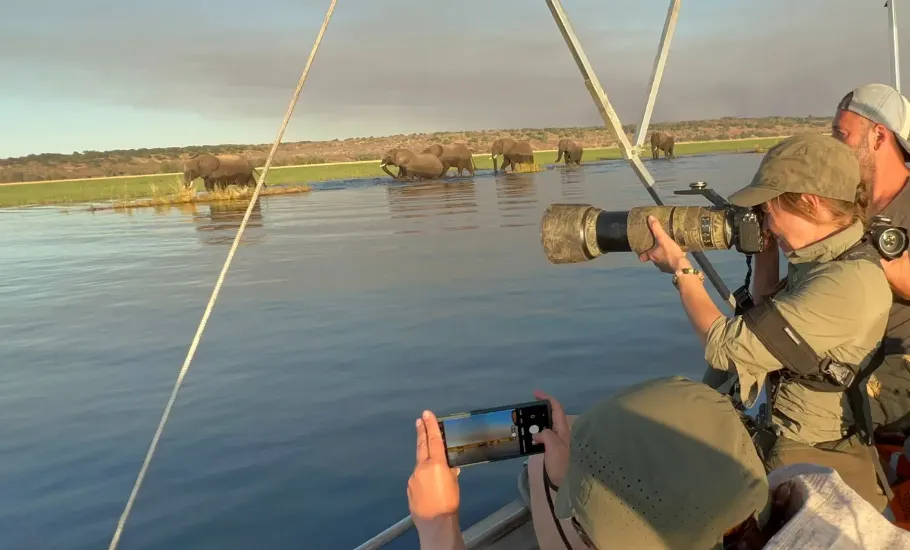 Turyści outventure.life fotografujący z łodzi słonie na brzegu rzeki Chobe w Botswanie