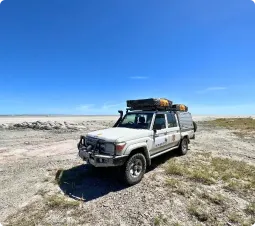 Samochód terenowy Toyota Land Cruiser wyprawy outventure.life na solnisku Makgadikgadi w Botswanie – self-drive safari z namiotem dachowym na tle błękitnego nieba.
